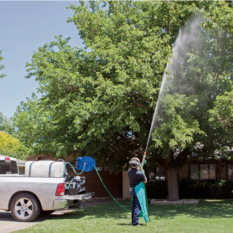 Man using skid sprayer to spray a tree