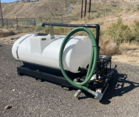 skid sprayer on road with green hose