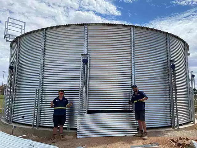 Two installers holding their thumbs up after intalling the panels on One Clarion corrugated tank