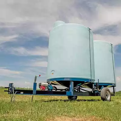 Cone bottom trailer with two blue tanks attached