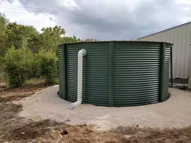 Green corrugated tank installed on a sand base