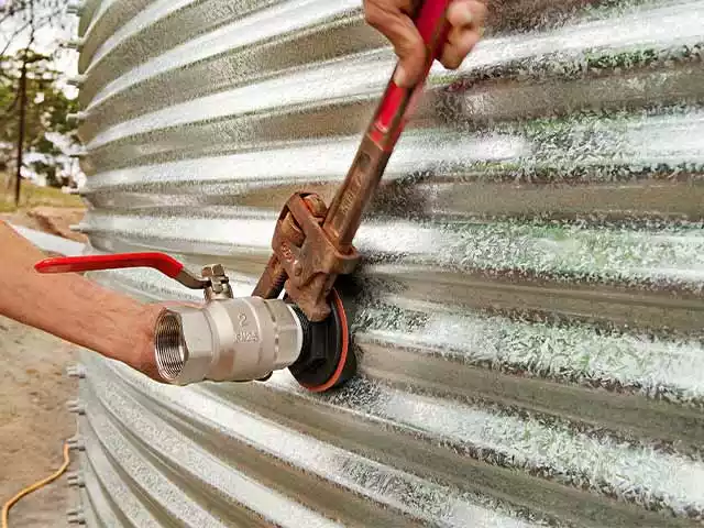 Man installing a fitting on a corrugated water tank