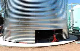 Corrugated steel tank installed on a concrete pad with a panel missing on the bottom