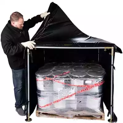 Man covering a pallet of materials with a heater blanket.