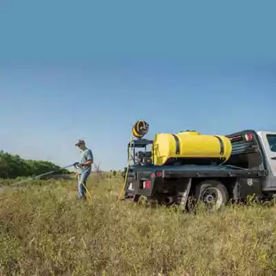 Man using an elliptical skid sprayer to spray his field